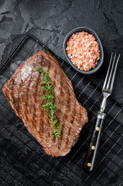 istock Roasted medium rare flank beef steak with thyme. Black background. Top view 1502881227