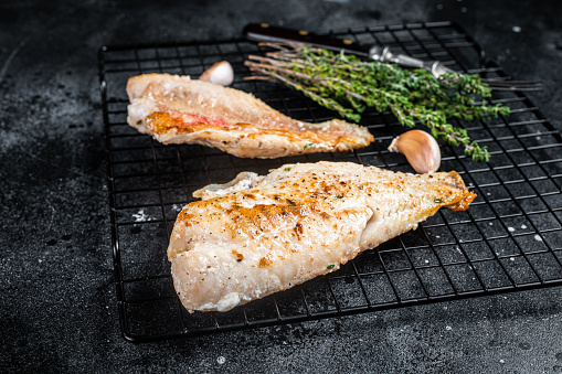 Grilled sea red perch fillet, Snapper fish on a rack. Black background. Top view.