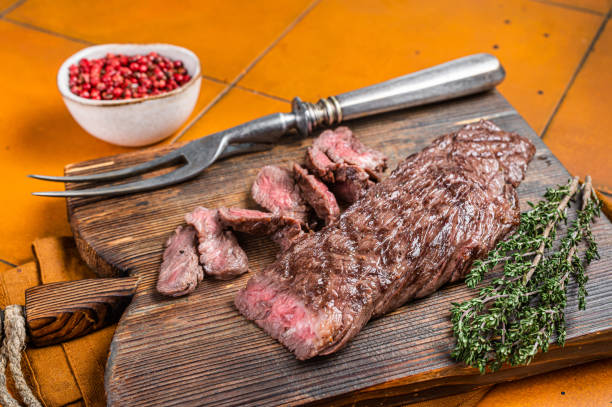 grilled medium rare machete or skirt beef meat steak on wooden cutting board. orange background. top view - top sirloin imagens e fotografias de stock