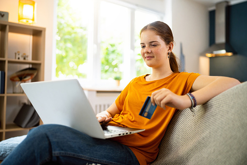 Redhead Caucasian teenage girl, using a laptop, while online shopping at home