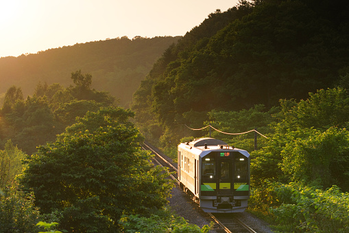 Otaru-city, Hokkaido, Japan - June 26, 2023 : Clear sky and H100 DECMO Local train which runs receiving sunset beam
