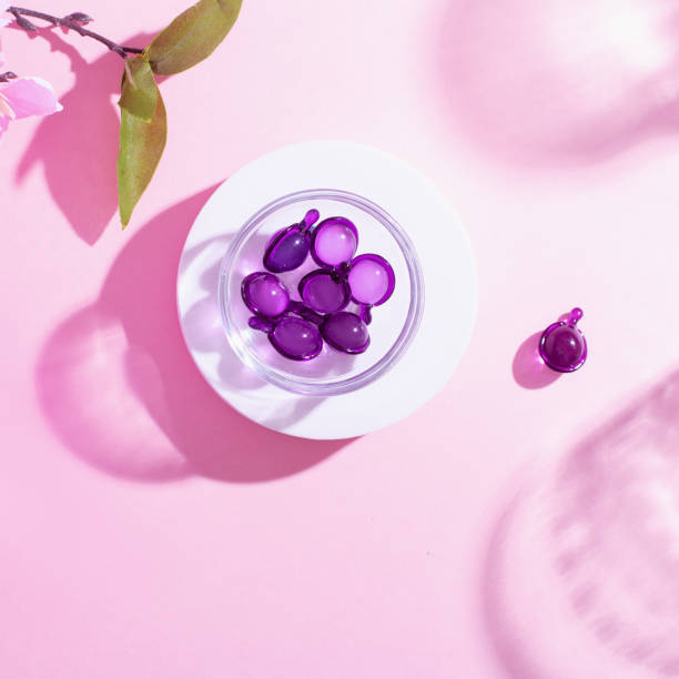 cápsulas de vitaminas en rosa, color púrpura, primer plano sobre fondo rosa, vista superior - spa treatment capsule body care hair gel fotografías e imágenes de stock