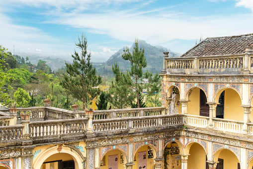 Bac Ha, Vietnam-April 2023; Upper level of dilapidated Hoang A Tuong Palace with a blend of European and Chinese architectural styles, now a museum about Hmong  people and mountains in background