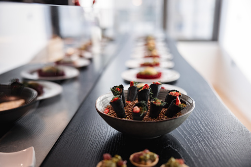 Delicious food prepared by a professional chef placed on the kitchen counter, ready to be served to the guests of the private dinner party. The food is beautifully plated and looks luxurious.