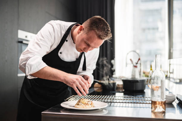 Attractive Blonde Professional Private Chef Plating A Dessert In A Modern Kitchen