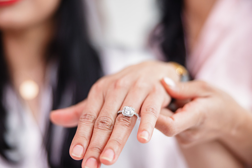 Close-up of a female's hand with a ring on. The bride-to-be is showing off her expensive engagement ring to her friends during a bachelorette party.