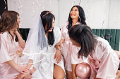 A Bride-To-Be And Her Bridesmaids Laughing While Celebrating A Bachelorette Party In A Hotel Room