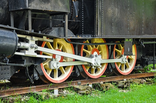 A black train car with yellow and red wheels seen from an angle