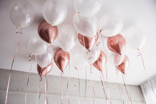Pink and white balloons covering the ceiling of a hotel bedroom before a celebration. Cute bachelorette decorations.