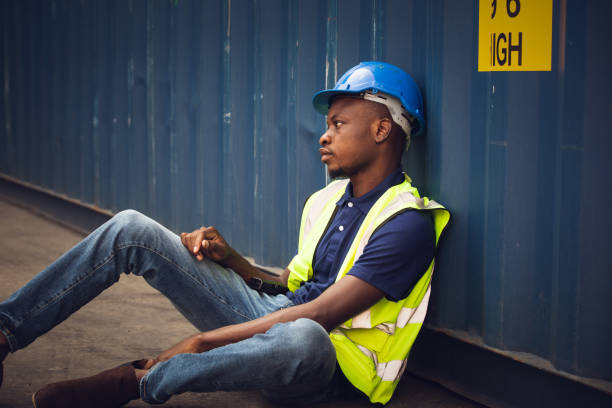 istock African American worker and resting sit at container box at construction site. Contractor or builder man tired and exhausted from work. 1502885556