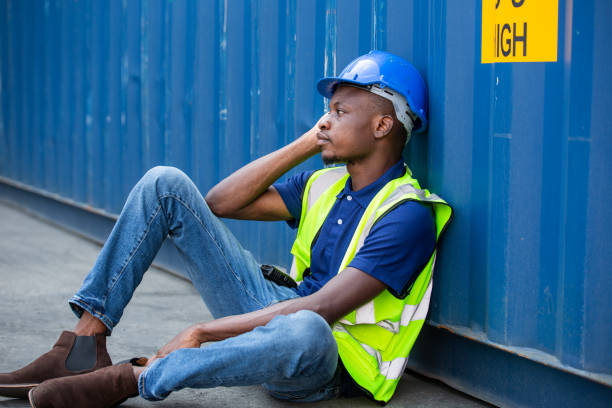 istock African American worker and resting sit at container box at construction site. Contractor or builder man tired and exhausted from work. 1502885560