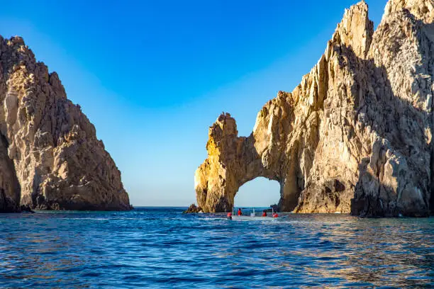 Photo of Tourists visiting the arc of Cabo San Lucas sailing along the Gulf of California that joins the Sea of Cortez with the Pacific Ocean at the land's end in Baja California Sur.