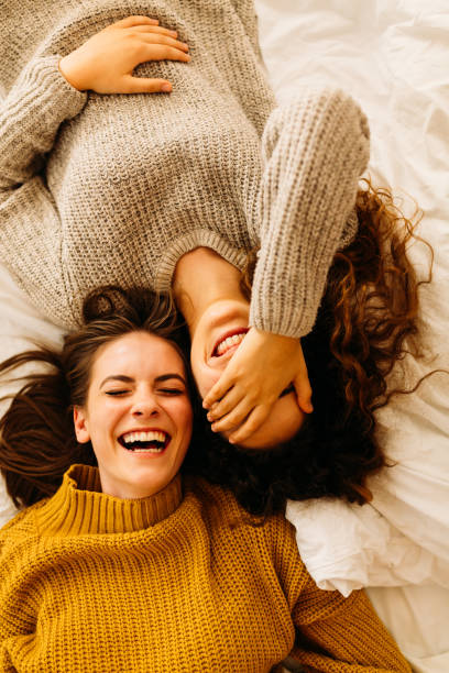 Two young women lying on back and laughing together