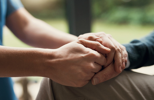 Closeup, hands and support with hope, empathy and praying with trust, healing together and grief. Zoom, elderly woman and person touching palms, compassion or sympathy with bonding, comfort and loss