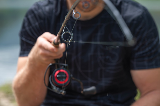 Holding fishing rod close up on the line and reel, copy space summer activities