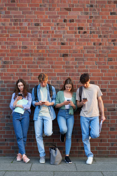 istock Group of university students browsing phones next to university campus building 1502898270