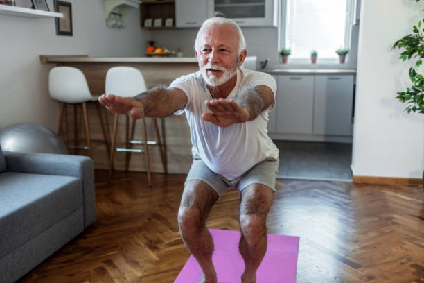 istock Caucasian senior man doing stretching exercise while sitting on yoga mat at home. Attractive mature man training indoors working out legs. 1502900501