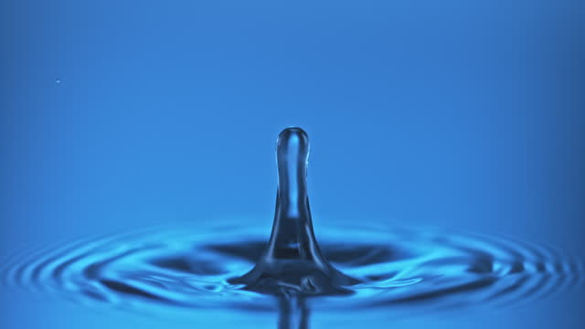 SLO MO LD Droplet of water falling into calm water and bouncing off the surface