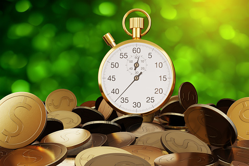 Golden stop watch on a heap of gold coins with green bokeh background. Illustration of the concept of time is money and time value of money
