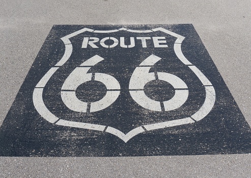 A vintage Route 66 highway sign painted on an asphalt highway in a rural area