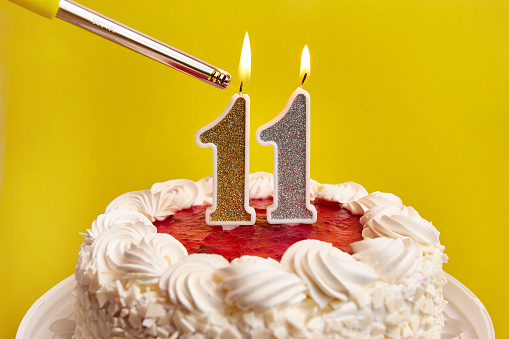 A candle in the form of the number 11, stuck in a holiday cake, is lit. Celebrating a birthday or a landmark event. The climax of the celebration.