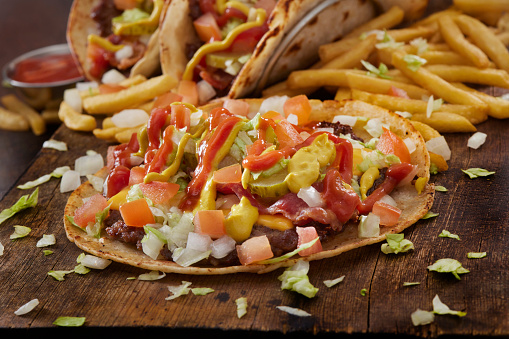 The Viral Smash Burger Taco with Bacon, American Cheese, Pickles, Onions, Lettuce, Tomatoes, Ketchup, Mustard and Fries