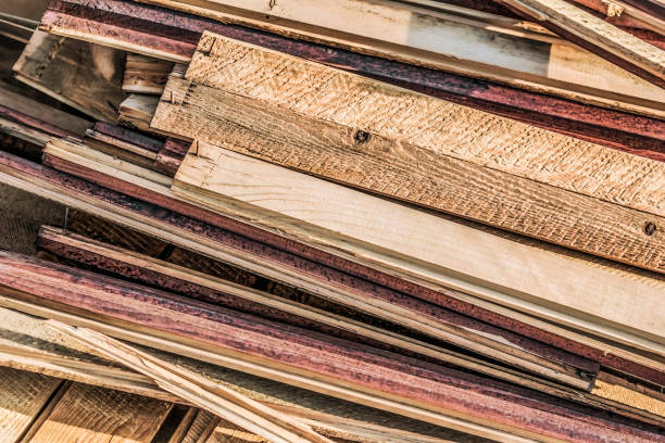 Heap of Scrapped Old Weathered Cracked Knotted Pine Wood Decking Planks with Crooked Rusty Nails Sticking Out stock photo