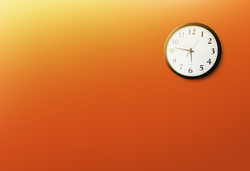 Clock on orange wall showing the time 5.47.