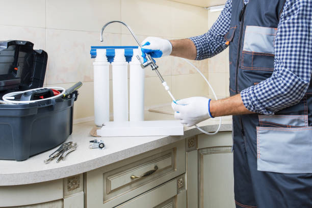 istock Water purification filter install. Plumber hands in gloves replace water filter cartridges at home kitchen. 1502927205