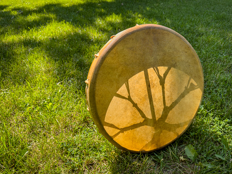 handmade, native American style, shaman frame drum on a grass backlit by sun