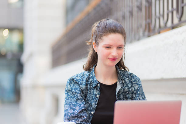 istock Young Adult Woman Smiling While Using Laptop, Wireless Internet Technology, and Communicating in Architectural Setting 1502932609