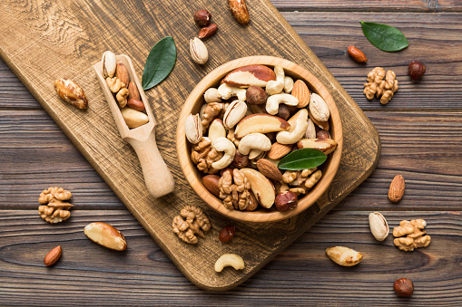 mixed nuts in bowl. Mix of various nuts on colored background. pistachios, cashews, walnuts, hazelnuts, peanuts and brazil nuts