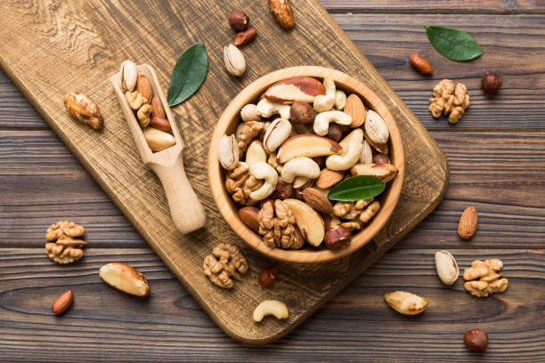 mixed nuts in bowl. mix of various nuts on colored background. pistachios, cashews, walnuts, hazelnuts, peanuts and brazil nuts - healthy eating healthcare and medicine healthy lifestyle people imagens e fotografias de stock