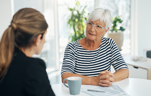 Senior woman, advisor and talking about insurance, savings or retirement plan. Elderly client person and a banker, broker or consultant at a table for a discussion, chat and meeting about finance
