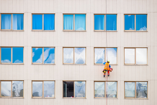 Minsk, Belarus - April 11, 2022: Industrial climber washes windows on facade of a building. Front view