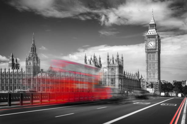 Red double decker bus with motion blur on Westminster bridge, Big Ben in the background, in London, UK. Black and white with selective color