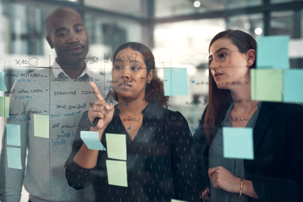 istock Business men, women and planning by glass, notes and writing for strategy, problem solving or teamwork at startup. Group, collaboration and vision with brainstorming, idea and discussion with mindset 1502935761