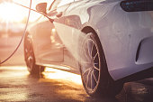 Washing rims at a manual car wash during sunset.