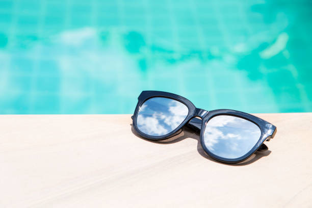 istock Sunglasses with sky reflection on swimming pool edge with space on blue water background 1502940793