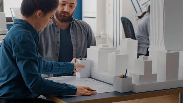 istock Close up of man and woman designing blueprints plan, analyzing building model 1502942174