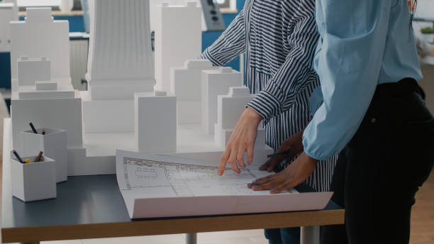 istock Close up of team of colleagues using blueprints plan to design urban construction on table 1502943012