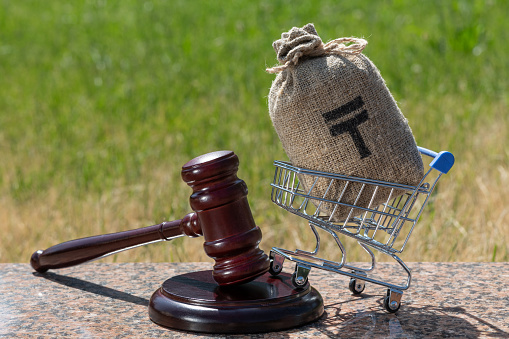 Judge gavel and money bag with Kazakh currency symbol - tenge on natural background