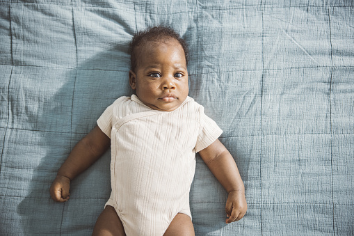 Portrait of African American newborn baby laying on bed.