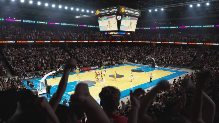 High Angle Establishing Wide Shot of a Whole Arena of Spectators Watching a Basketball Championship Game. Teams Play, Crowds of Fans Raise Hands and Cheer. Sports Channel Live Television Broadcast