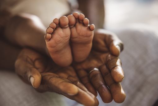 Cropped shot of a father holding her baby’s feet
