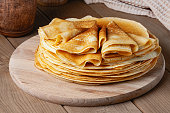 Thin pancakes on a wood plate. Homemade crepes, tasty food. Staple of yeast pancakes, traditional for Russian pancake week (Shrove tide). Thin pancake with crispy crust