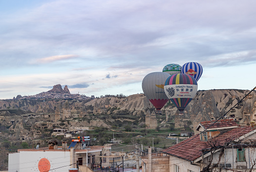 Goreme, Turkey - April 12, 2023: A picture of hot air balloons flying over the town of Goreme at sunrise.