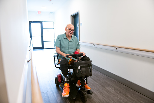 Senior amputee rides mobility scooter in affordable housing apartment building