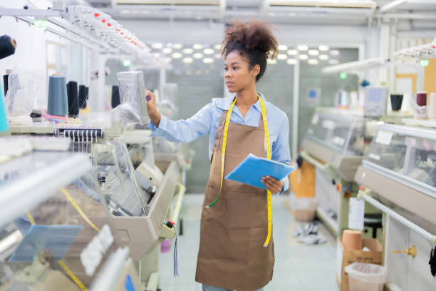 istock female designer be a seamstress Pushing button on a sewing machine control panel. Holding a list of notes. Fashion design item, clothes with tape measure and spool of thread. in the weaving industry 1502953567