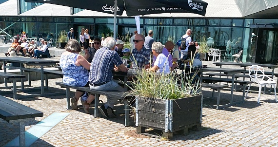 People sitting  under parasols at the square in front of The Culture Yard. The photo was taken on June 10th, 2023 in Helsingør, Denmark close to Kronborg, the Castle of Hamlet..